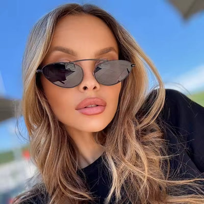 Olyra aviator women's sunglasses in black metal frame with black polycarbonate lenses, 100% UV protection, worn by female model outdoors, facing camera with slight smile expression, hands not visible