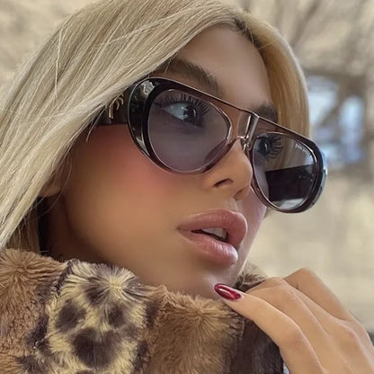 Nyara shield women's shades in brown acetate frame with soft blue TAC lenses, 100% UV protection, worn outdoors by female model facing slightly right, looking right, hand touching fur jacket collar